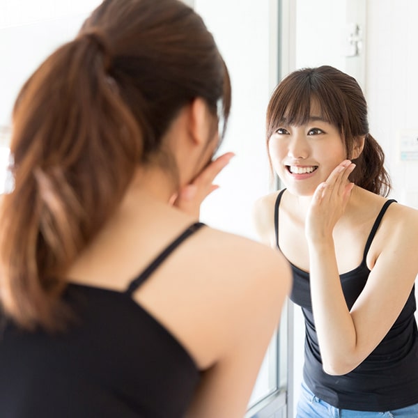 A picture of a woman looking at herself in the mirror and smiling