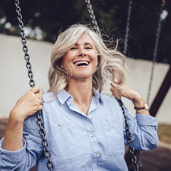 A picture of a woman laughing on a swing