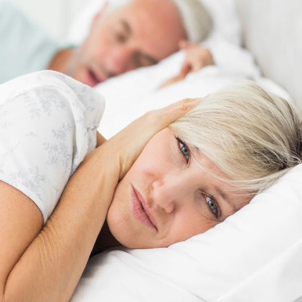 Woman covering her ears because of the snoring husband